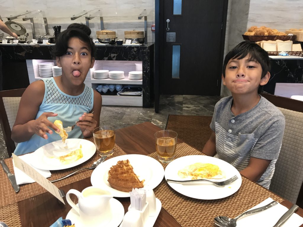 a couple of kids sitting at a table with food