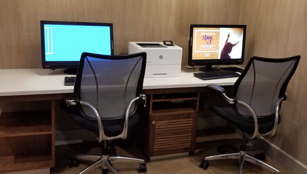 a desk with two computers and a printer