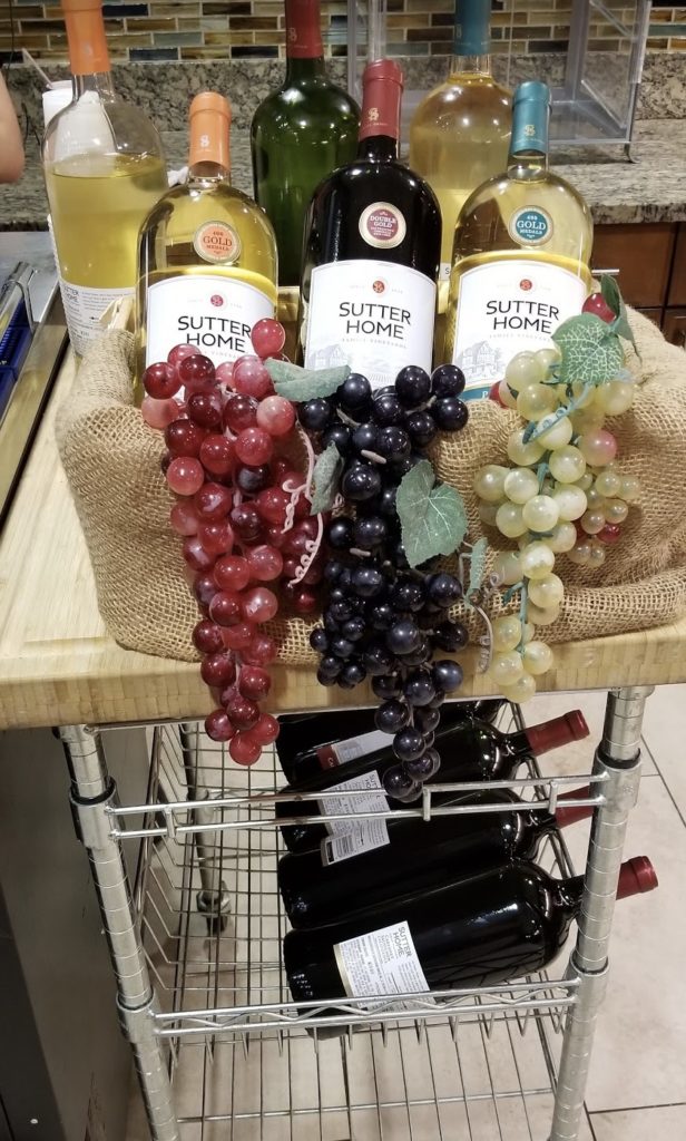 a cart with wine bottles and grapes