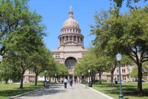 a large building with a dome on the top with Texas State Capitol in the background