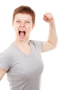 a woman with short hair yelling and holding her fist up