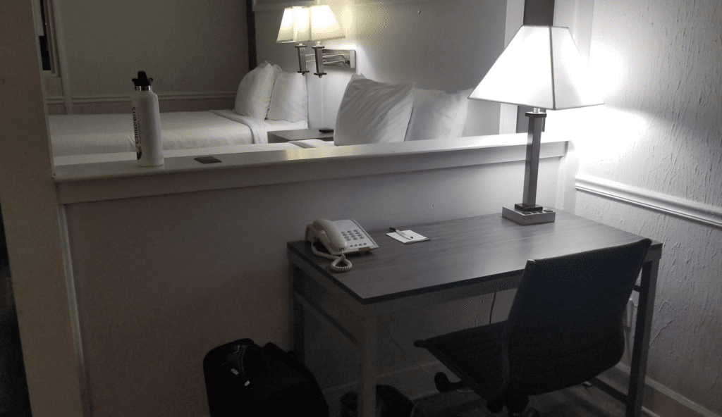 a desk with a phone and a lamp in a hotel room