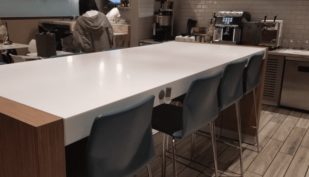 a white table with blue chairs in a room with people in the background