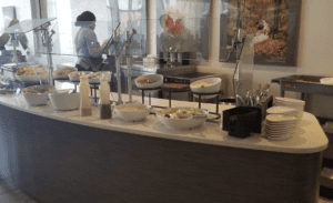 a woman standing behind a counter with food in bowls