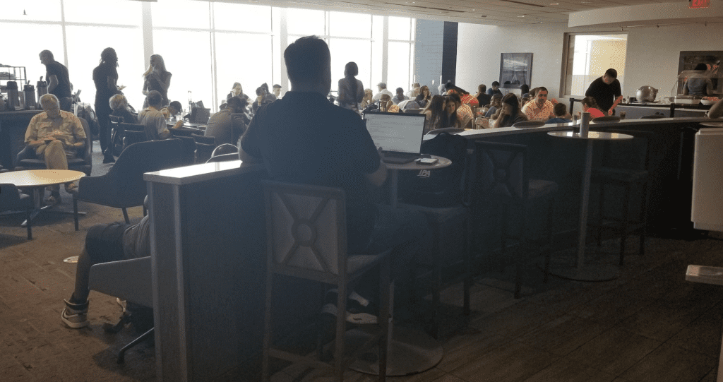 a group of people sitting at tables in a room with a laptop