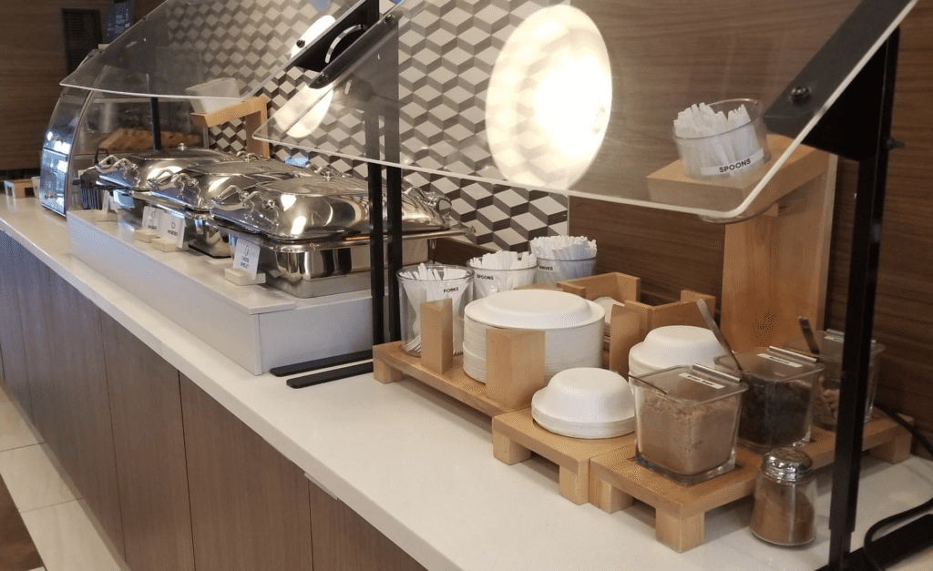 a buffet table with food containers and a glass cover