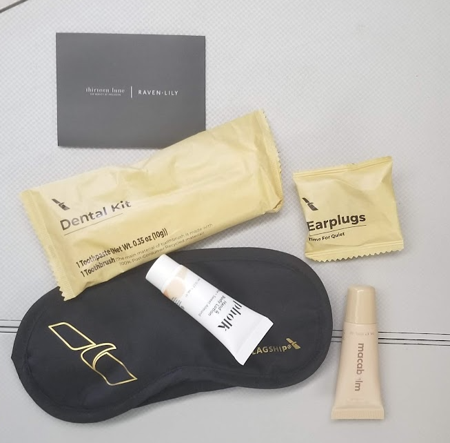 a black eye mask and a tube of cream and a small tube of cream on a white surface