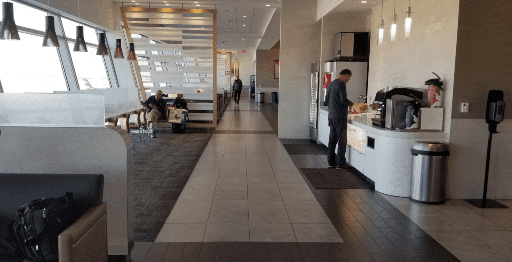 a man standing in a room with a counter and people sitting on the floor