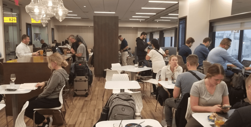 a group of people sitting at tables in a room with luggage