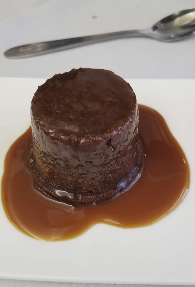 a chocolate pudding with sauce on a white plate