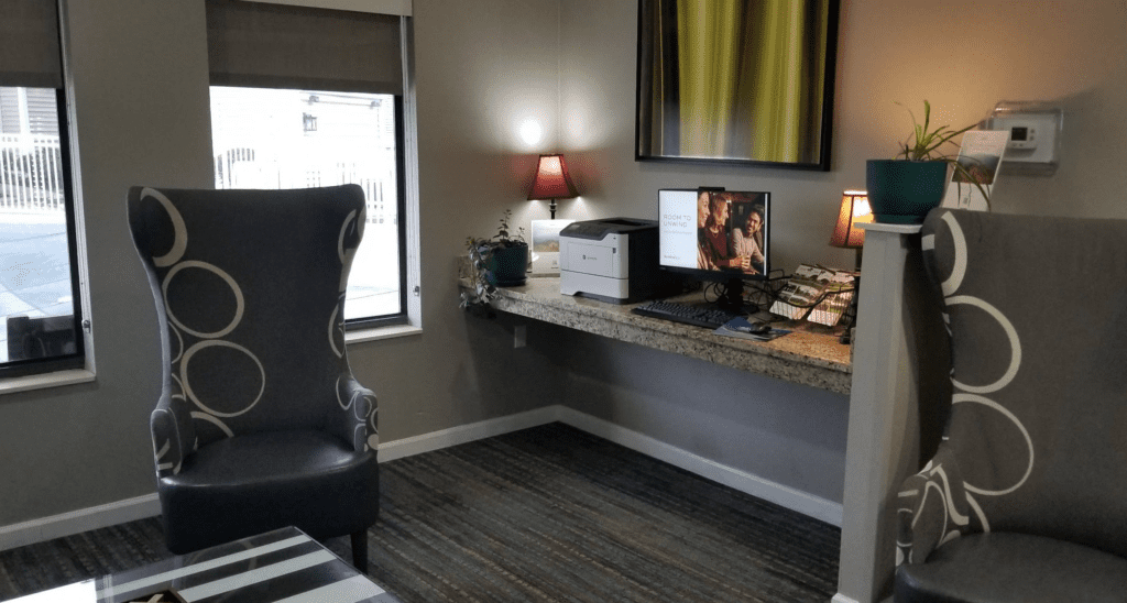 a desk with a computer and a chair in a room